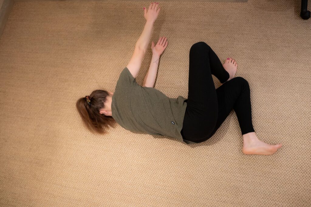 Personne pratiquant un mouvement fluide de MUNZ FLOOR sur un tapis beige, illustrant un cours en ligne