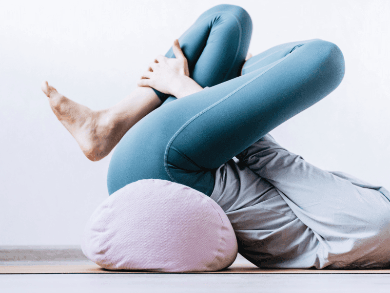 Personne pratiquant le yoga avec un coussin.