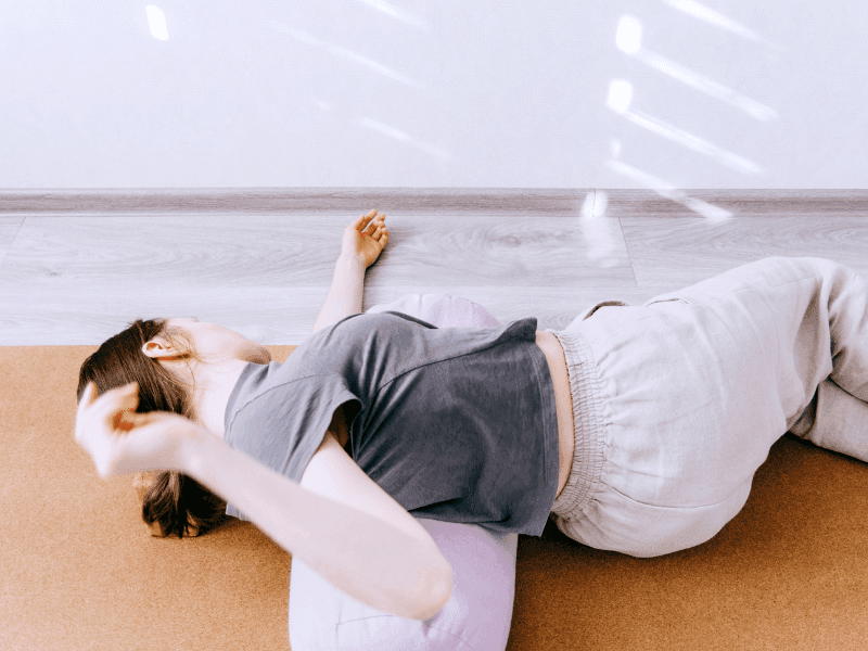 Femme allongée, posée sur un coussin de yoga.